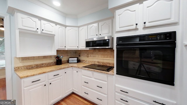 kitchen with tasteful backsplash, white cabinetry, black appliances, and light stone countertops