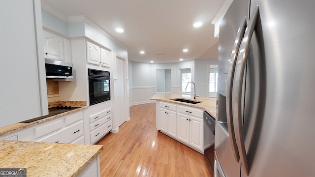 kitchen with light stone counters, white cabinetry, stainless steel appliances, and a sink