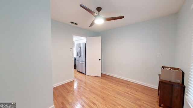 unfurnished bedroom featuring light wood-type flooring, baseboards, visible vents, and stainless steel fridge with ice dispenser