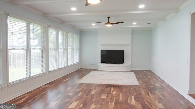 unfurnished living room with a wealth of natural light, beam ceiling, dark wood finished floors, and ceiling fan