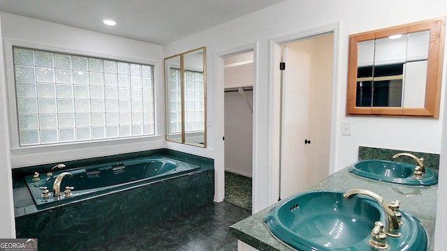 bathroom with a garden tub, double vanity, a sink, and recessed lighting