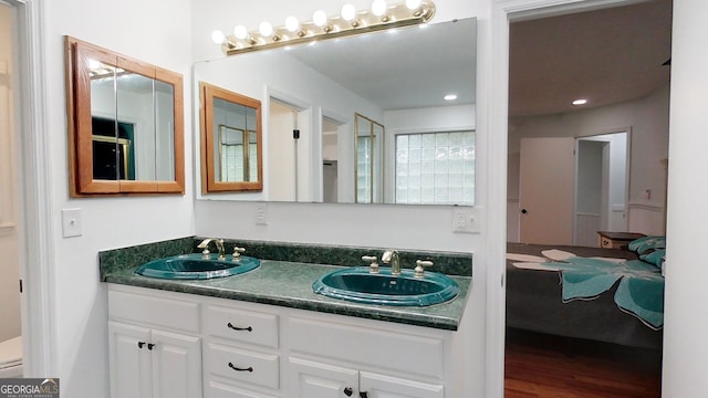 bathroom with double vanity, a sink, and wood finished floors