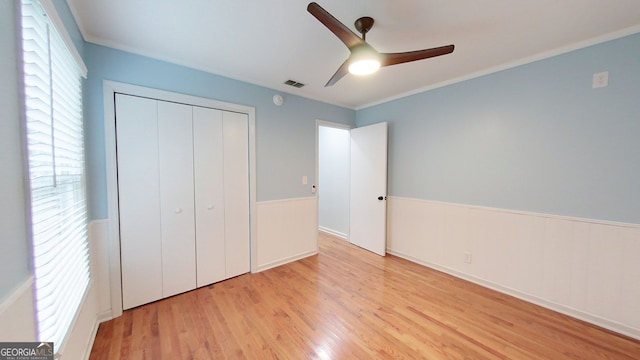 unfurnished bedroom featuring visible vents, a ceiling fan, light wood-style flooring, crown molding, and a closet