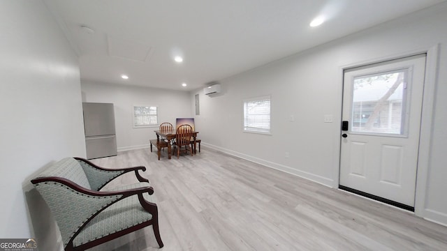 living area featuring light wood finished floors, a wall unit AC, recessed lighting, and baseboards