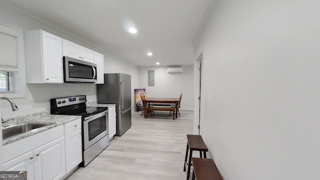 kitchen with a wall unit AC, white cabinetry, appliances with stainless steel finishes, and a sink