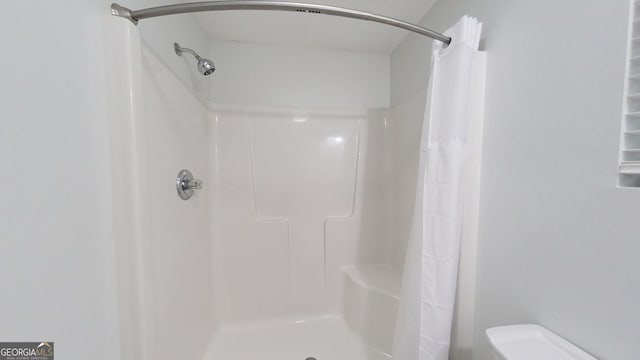 bathroom with toilet and a shower with shower curtain