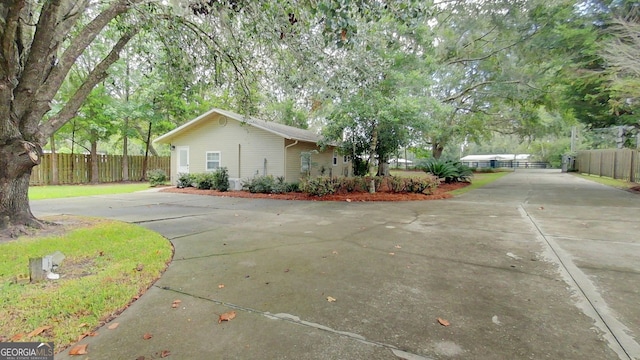 view of side of home with concrete driveway and fence