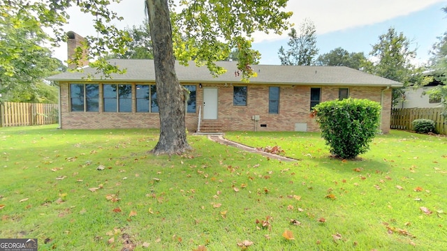 rear view of house with entry steps, crawl space, fence, and a lawn