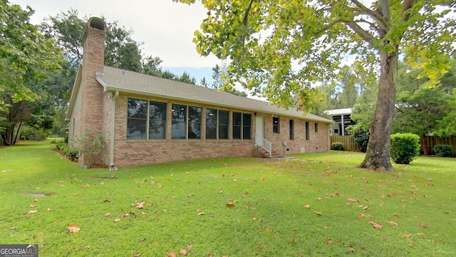 back of property with brick siding, a chimney, a lawn, entry steps, and crawl space