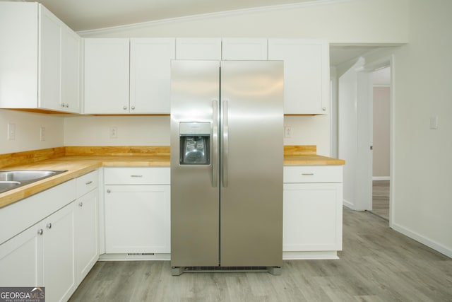 kitchen with lofted ceiling, wood counters, white cabinets, stainless steel refrigerator with ice dispenser, and light wood finished floors