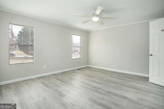 empty room with light wood finished floors, ceiling fan, baseboards, and crown molding