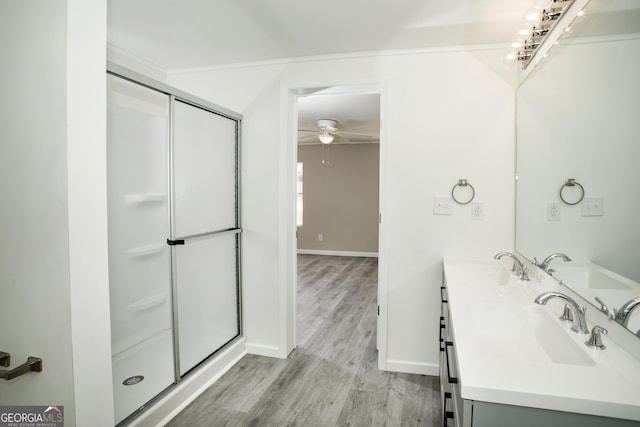 bathroom with a sink, wood finished floors, a ceiling fan, a shower stall, and double vanity