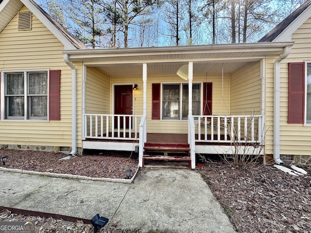 view of exterior entry with a porch and crawl space