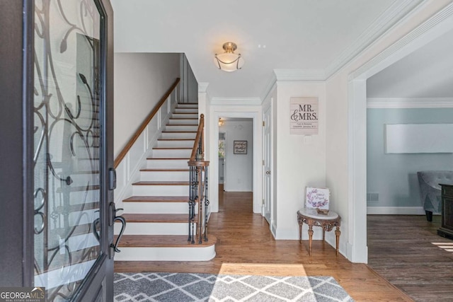 foyer entrance featuring baseboards, visible vents, wood finished floors, stairs, and crown molding