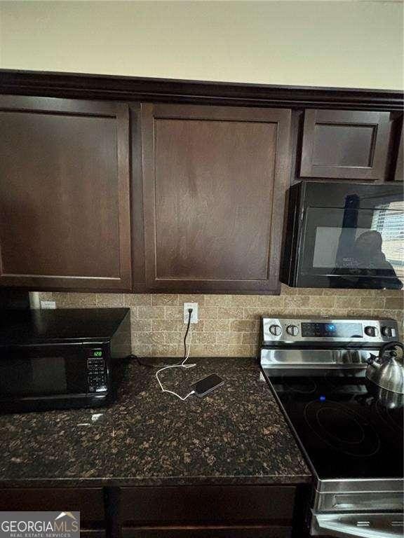 kitchen with black microwave, stainless steel range with electric cooktop, dark brown cabinets, tasteful backsplash, and dark stone countertops