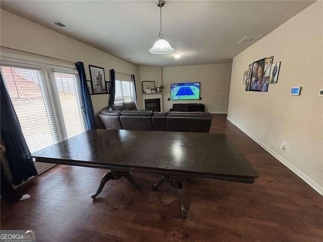 dining area featuring dark wood-type flooring, visible vents, a fireplace, and baseboards