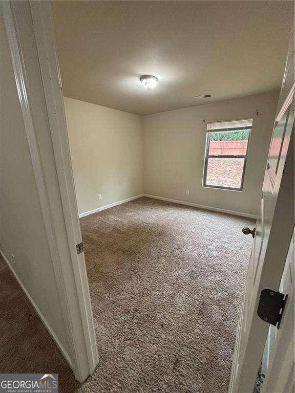 unfurnished room featuring carpet, visible vents, and baseboards