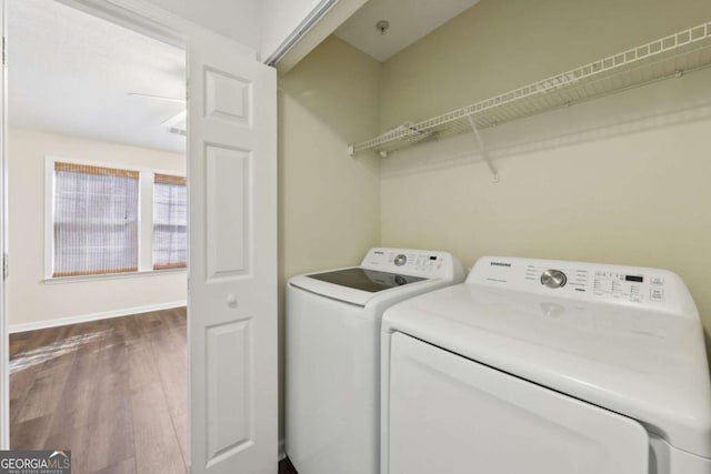 laundry room with laundry area, washer and clothes dryer, wood finished floors, and baseboards