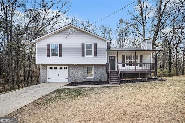 split level home with a porch, a garage, driveway, a front lawn, and a chimney