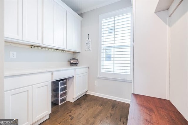 unfurnished office featuring dark wood-style floors, baseboards, and ornamental molding