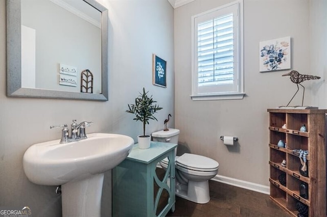 half bathroom featuring a sink, wood finished floors, toilet, and baseboards