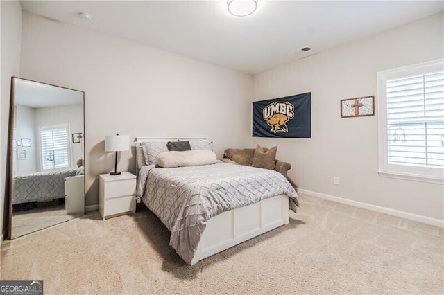 bedroom featuring baseboards, multiple windows, visible vents, and light colored carpet