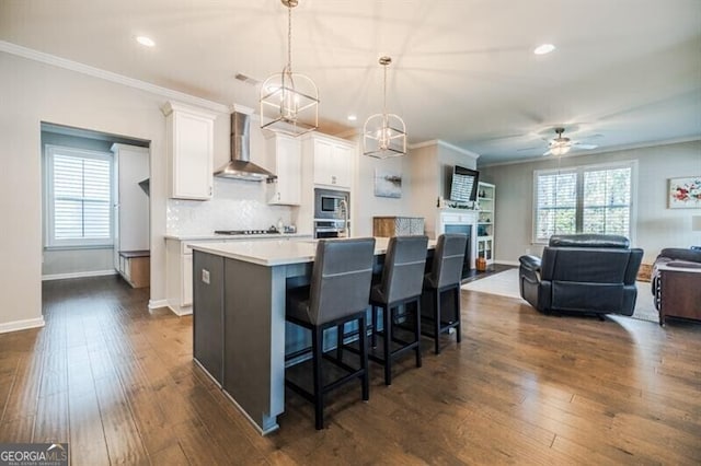 kitchen with dark wood-type flooring, white cabinetry, crown molding, and wall chimney exhaust hood