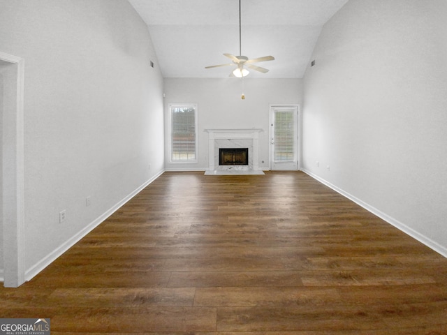 unfurnished living room featuring dark wood-style floors, ceiling fan, a fireplace, and baseboards