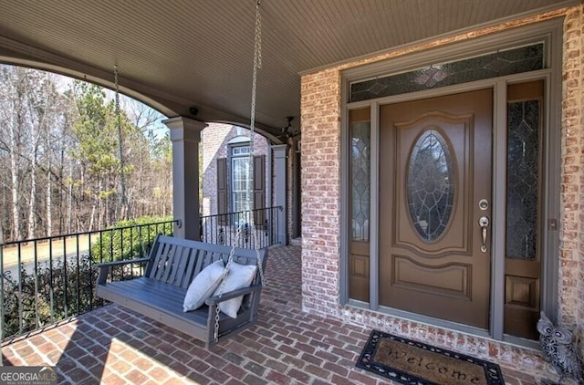 entrance to property with a porch and brick siding