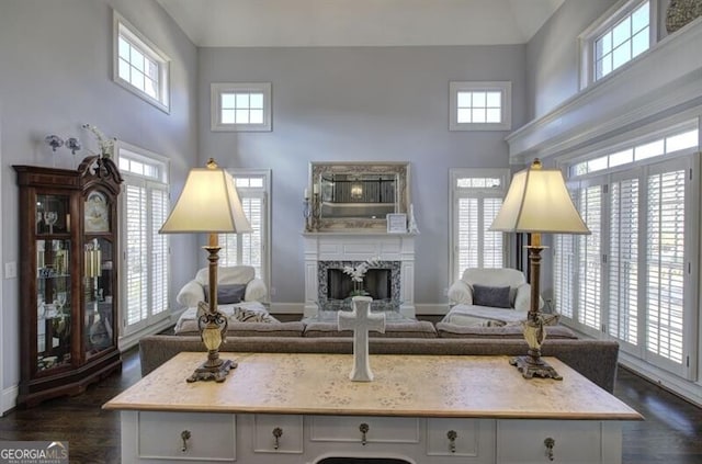 living area with dark wood-type flooring, a high end fireplace, baseboards, and a high ceiling