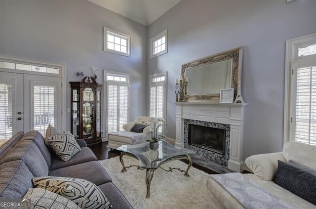 living room with a high end fireplace, french doors, a high ceiling, and wood finished floors