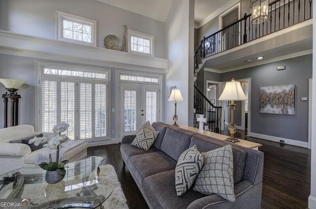 living room featuring a towering ceiling, baseboards, stairway, and wood finished floors