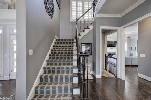 stairs with crown molding, baseboards, and wood finished floors