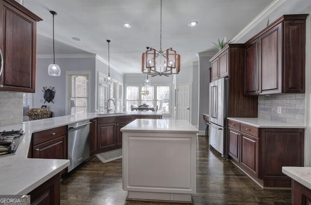 kitchen with dark wood-type flooring, a kitchen island, a sink, light countertops, and appliances with stainless steel finishes