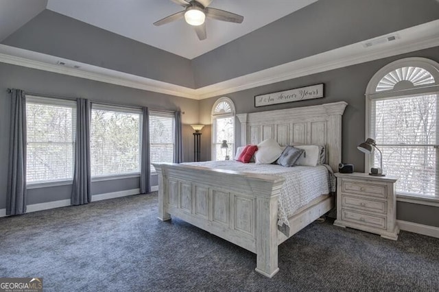 bedroom with baseboards, a ceiling fan, ornamental molding, a tray ceiling, and dark colored carpet