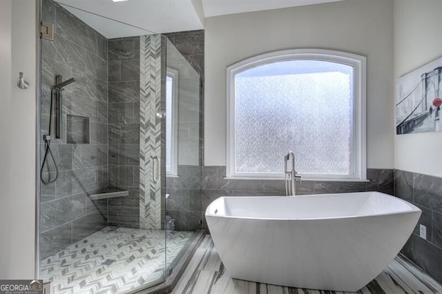 full bath with tile walls, a freestanding tub, a wainscoted wall, and a shower stall