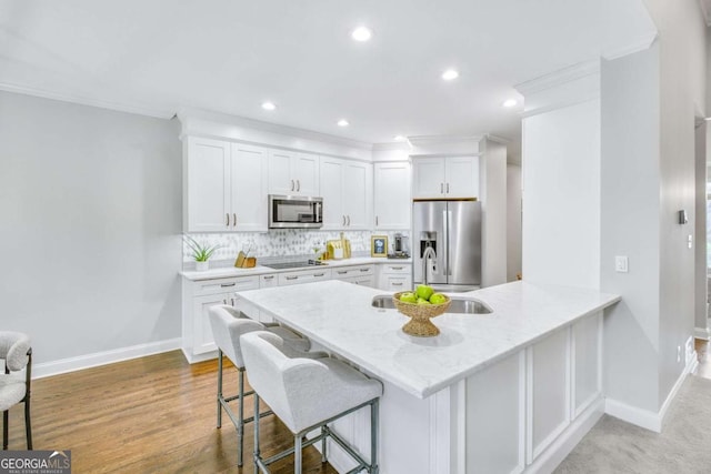 kitchen with stainless steel appliances, a kitchen bar, and white cabinetry