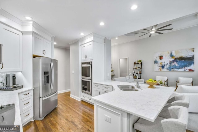 kitchen featuring appliances with stainless steel finishes, a kitchen bar, a sink, and white cabinets