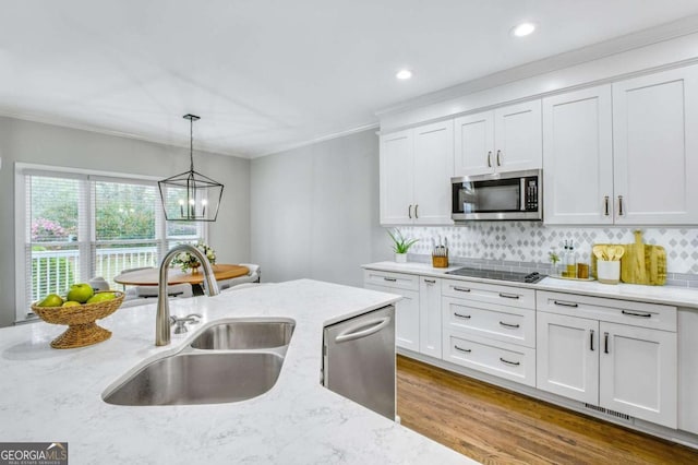 kitchen featuring pendant lighting, stainless steel appliances, a sink, and white cabinets