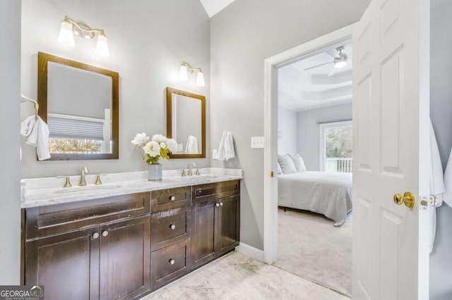 ensuite bathroom with a raised ceiling, a sink, ensuite bath, and double vanity