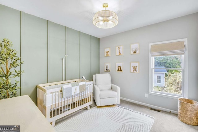 bedroom featuring a notable chandelier, carpet flooring, visible vents, baseboards, and a nursery area