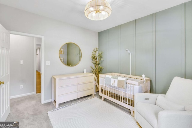 bedroom featuring light colored carpet, a crib, and baseboards