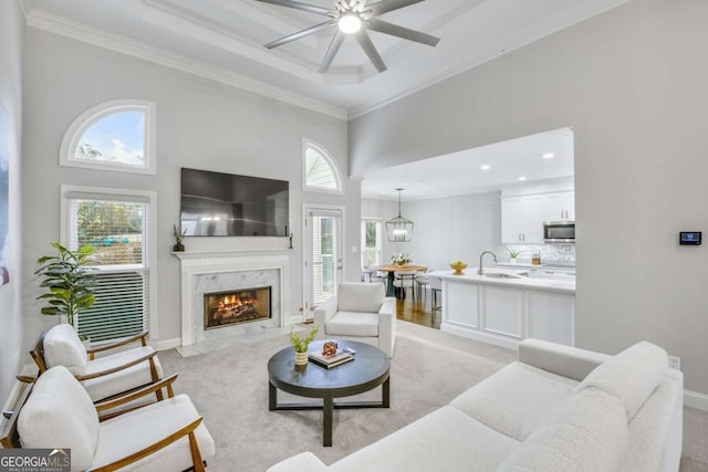 living room with ornamental molding, light colored carpet, a fireplace, and baseboards