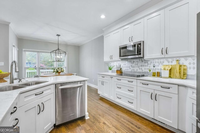 kitchen featuring a sink, white cabinetry, appliances with stainless steel finishes, light stone countertops, and decorative light fixtures