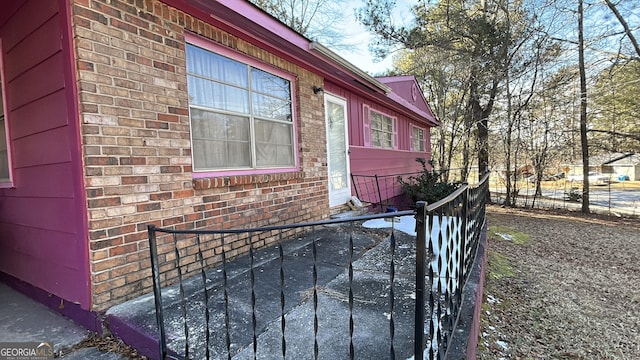 view of side of property featuring fence and brick siding