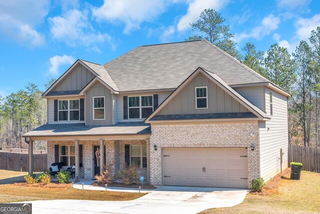 craftsman house with fence, brick siding, board and batten siding, and covered porch