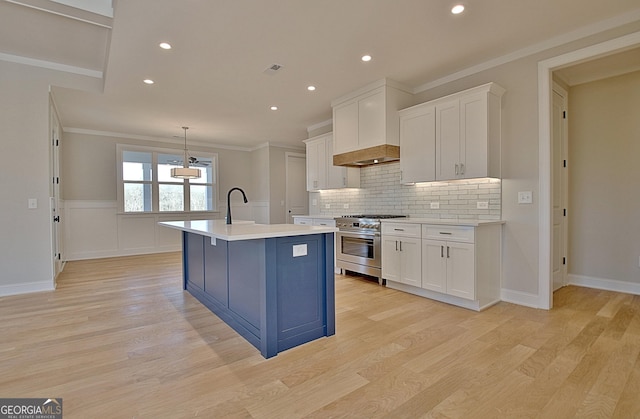 kitchen featuring white cabinets, a kitchen island with sink, light countertops, and stainless steel stove