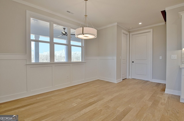 unfurnished dining area with ceiling fan, ornamental molding, light wood-type flooring, and visible vents
