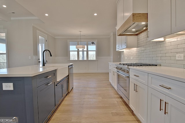 kitchen with appliances with stainless steel finishes, white cabinets, light countertops, and decorative light fixtures