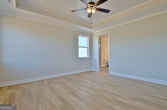 unfurnished room featuring light wood-type flooring, a raised ceiling, a ceiling fan, and baseboards